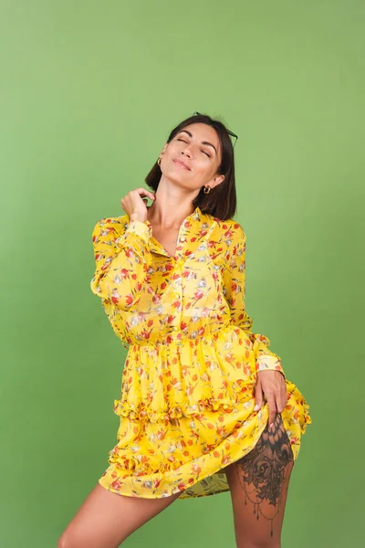 黄色の夏のドレスとサングラスの美しい女性 緑のスタジオの背景 幸せな正陽気な喜びの感情 — ストック写真