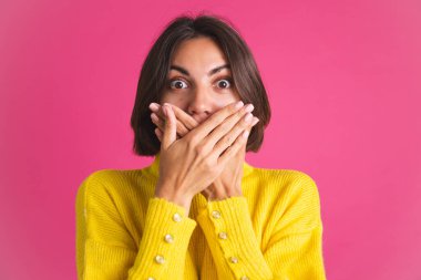 Pembe arka planda izole edilmiş, parlak sarı süveterli güzel bir kadın.