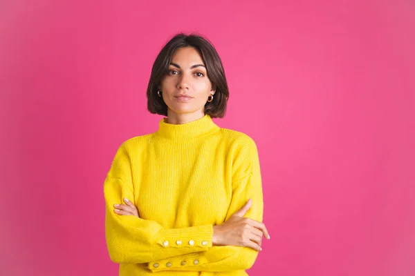 美しいです女性で明るい黄色のセーターでピンクの背景に隔離された表情でカメラに自信を持って笑顔 — ストック写真