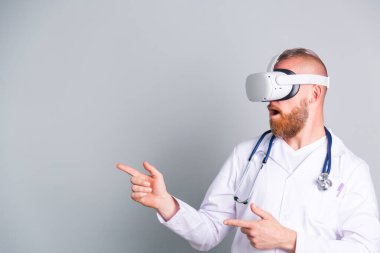 Gri arka planda yakışıklı erkek doktor sanal gerçeklik gözlüklerini sol tarafa çevirmiş.