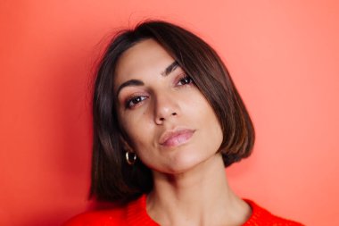 Kırmızı arka plandaki kadının yakın portresi kameraya bakıyor