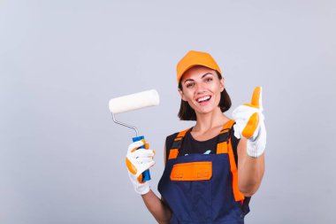 Gri arka planda paten fırçası olan ressam kadın gülümsüyor.