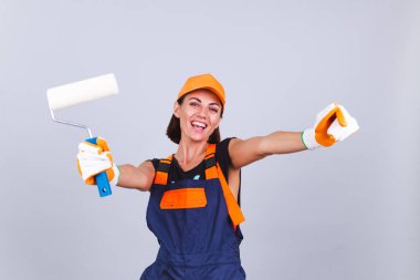 Gri arka planda paten fırçası olan, mutlu gülümseyen ressam kadın.