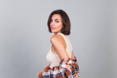 Üstte güzel bir kadın ve gri arka planda ekose bir gömlek makyajlı kendine güvenen bir gülümseme, mutlu duygular.