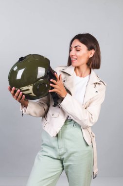 Gri arka planda deri ceketli ve kasklı bir kadın.