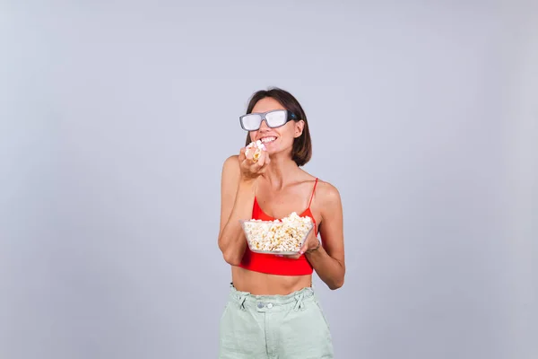 Beautiful woman on gray background in 3d cinema glasses with popcorn, cheerful happy positive emotions