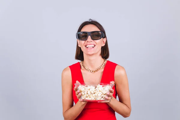 Beautiful woman on gray background in 3d cinema glasses with popcorn, cheerful happy positive emotions