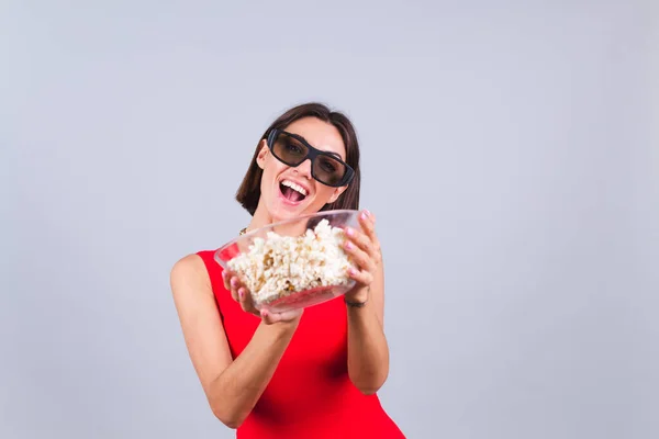 Beautiful woman on gray background in 3d cinema glasses with popcorn, cheerful happy positive emotions