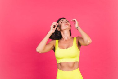 Pembe arka planda parlak spor kıyafetli güzel, fit bir kadın. Heyecanlı, hareketli, mükemmel vücut geliştirme motivasyonu.