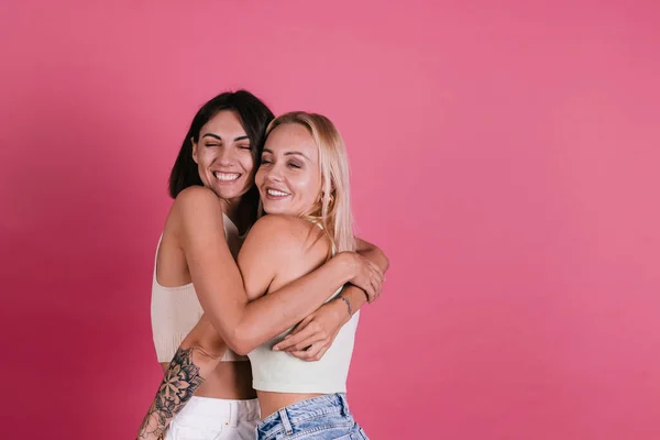 Two Girl Friends Casual Pink Background Love Hug Each Other — Stock Photo, Image