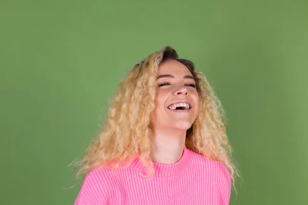 若いですブロンド女性とともに長いです巻き毛でピンクセーターで緑の背景肯定的な笑顔見てへカメラ笑い陽気に — ストック写真