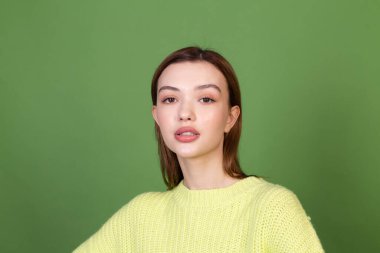 Temiz, doğal cilt ve makyajlı genç bir kadın. Yeşil arka planda kahverengi dudaklar. 