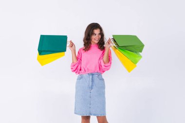 Çilli, hafif makyajlı, pembe kazaklı, beyaz arka planda kot etekli, şık bir kadın.