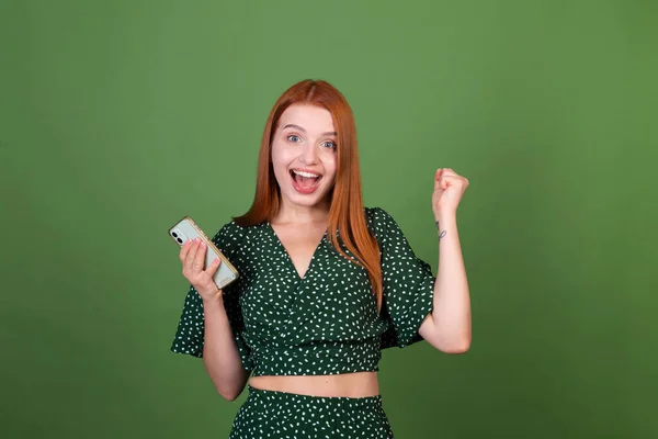 Yeşil Arka Planda Genç Kızıl Saçlı Kadın Cep Telefonuyla Mesajlaşıyor — Stok fotoğraf