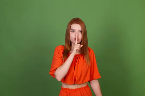 Νεαρή Κοκκινομάλλα Γυναίκα Casual Πορτοκαλί Μπλούζα Πράσινο Φόντο Δείχνει Shhh — Φωτογραφία Αρχείου