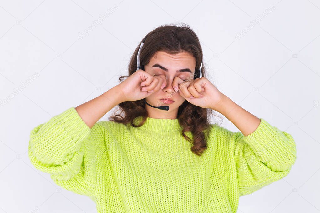 Young beautiful woman with freckles light makeup in sweater on white background with headphones helpline worker call centre manager sad tired bored