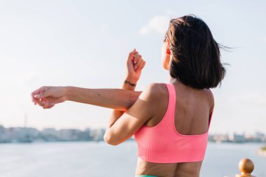 Günbatımında modern köprüde kollarını açarak spor yapan sporcu bir kadın.