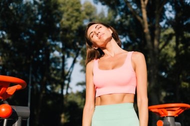 Spor salonundaki sporcu kadın gün batımında spor yaparken spor yaparken boynunu esnetiyor.