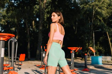 Spor kıyafetleri giyen sporcu kadın gün batımında açık hava spor sahasında pozitifken yaz havasının tadını çıkartıyor.