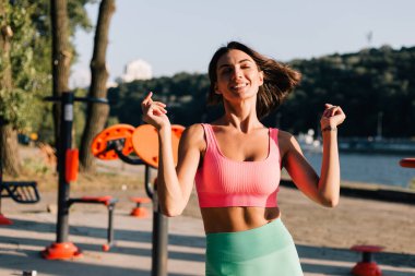 Spor kıyafetleri giyen sporcu kadın gün batımında açık hava spor sahasında pozitifken yaz havasının tadını çıkartıyor.