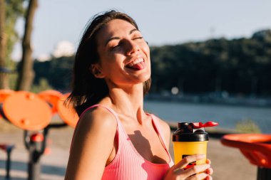 Spor kıyafetleri giyen sporcu kadın gün batımında açık hava spor sahasında pozitifti. Yaz havasının tadını çıkarıyordu.