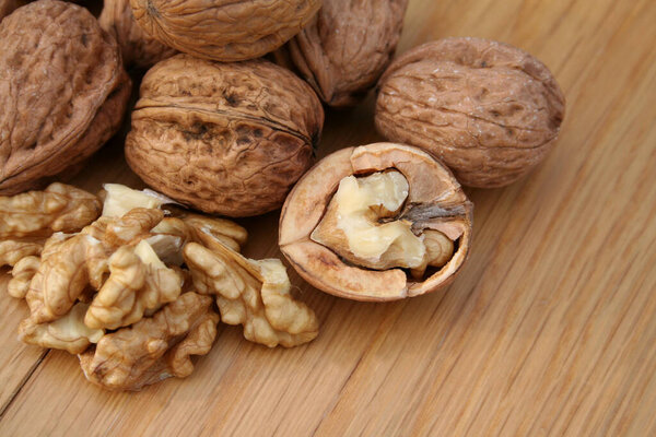 Целые и треснувшие грецкие орехи на деревянном фоне.