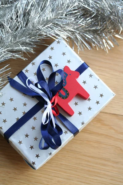 蓝色缎带的银礼品盒 木制背景的小红达拉马 — 图库照片