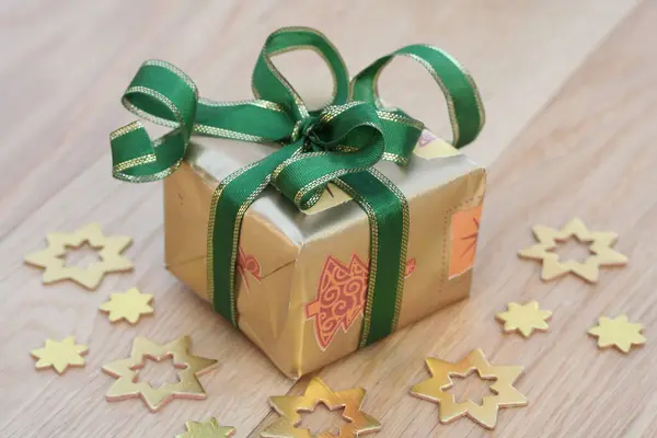 木制背景的金色礼品盒 上面有金色和绿色的圣诞彩带 — 图库照片