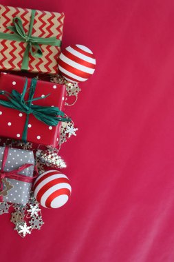 Çizgili cam top taşları ve kırmızı arka planda gümüş süslemeleri olan farklı Noel hediye kutuları. Noel şenliği arka planı