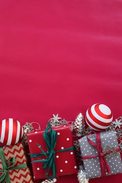 Çizgili cam top taşları ve kırmızı arka planda gümüş süslemeleri olan farklı Noel hediye kutuları. Noel şenliği arka planı