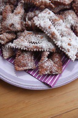 İtalyan Karnaval hamur işlerinin adı Crostoli ya da Cenci. Tahta bir tabakta. Geleneksel çikolatalı Crostoli 