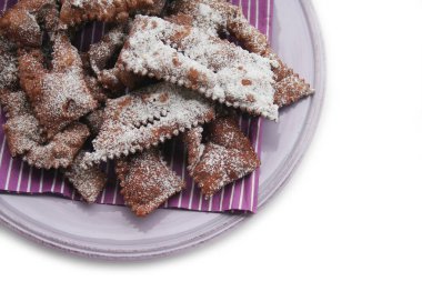 Beyaz arka planda izole edilmiş bir tabakta Crostoli veya Cenci adlı İtalyan Karnaval hamur işleri. Geleneksel çikolatalı Crostoli 