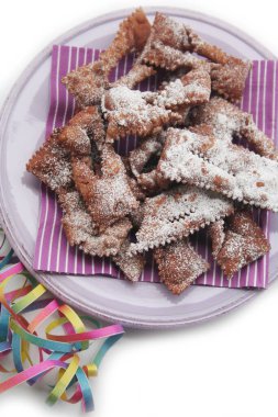 Beyaz arka planda izole edilmiş bir tabakta Crostoli veya Cenci adlı İtalyan Karnaval hamur işleri. Geleneksel çikolatalı Crostoli 