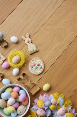 Paskalya geçmişi. Çok renkli çikolata yumurtaları, tavşan şeklinde kurabiyeler, çan ve yumurta ve ahşap masa süslemeleri. 