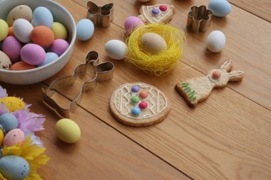 Paskalya geçmişi. Çok renkli çikolata yumurtaları, tavşan şeklinde kurabiyeler, çan ve yumurta ve ahşap masa süslemeleri. 