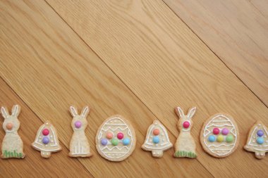 Paskalya kurabiyeleri yumurta, tavşan, çiçek ve çan şeklinde ahşap arka planda.