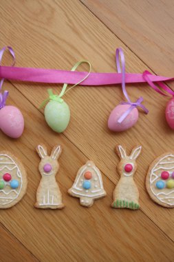 Paskalya kurabiyeleri yumurta, tavşan, çiçek ve çan şeklinde ahşap arka planda.