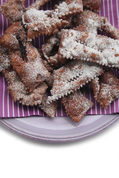 Beyaz arka planda izole edilmiş bir tabakta Crostoli veya Cenci adlı İtalyan Karnaval hamur işleri. Geleneksel çikolatalı Crostoli 