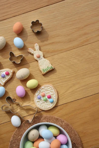 Paskalya geçmişi. Çok renkli çikolata yumurtaları, tavşan şeklinde kurabiyeler, çan ve yumurta ve ahşap masa süslemeleri. 