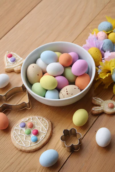 Paskalya geçmişi. Çok renkli çikolata yumurtaları, tavşan şeklinde kurabiyeler, çan ve yumurta ve ahşap masa süslemeleri. 