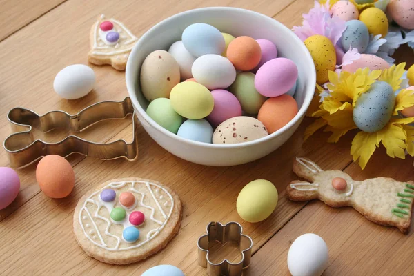 Paskalya geçmişi. Çok renkli çikolata yumurtaları, tavşan şeklinde kurabiyeler, çan ve yumurta ve ahşap masa süslemeleri. 