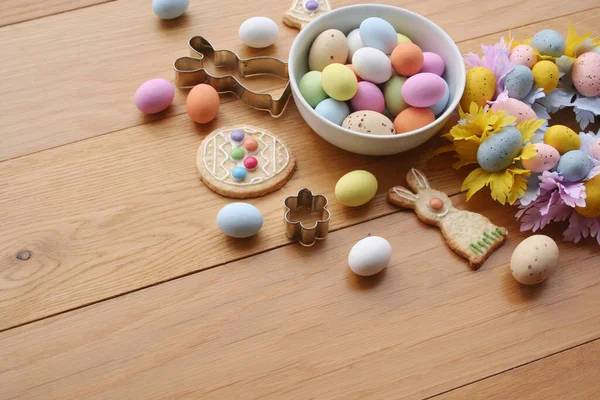 Paskalya geçmişi. Çok renkli çikolata yumurtaları, tavşan şeklinde kurabiyeler, çan ve yumurta ve ahşap masa süslemeleri. 