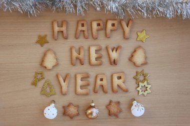 Mutlu yeni yıl kurabiyeleri. Ahşap masada, parlak süslemeli kurabiye mektupları.