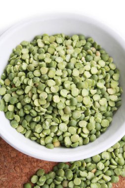 Beyaz arka planda bir kasede kuru yeşil bezelyeler. Pisum sativum.