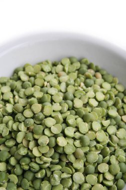Beyaz arka planda bir kasede kuru yeşil bezelyeler. Pisum sativum.
