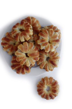 Beyaz arka planda beyaz seramik tabakta tarçın ve kamış şekerli ev yapımı puf elma halkaları.