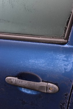 Kış mevsiminde buzla kaplı mavi arabanın yakın çekimi. Seçici odak noktasında arabanın yan görünümü