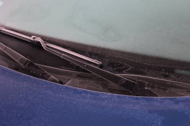 Mavi araba kış mevsiminde donla kaplı. Seçici odak noktasında arabanın ön görünümü.