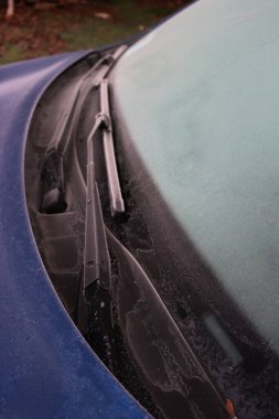 Mavi araba kış mevsiminde donla kaplı. Seçici odak noktasında arabanın ön görünümü.