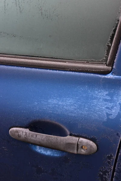 Kış mevsiminde buzla kaplı mavi arabanın yakın çekimi. Seçici odak noktasında arabanın yan görünümü